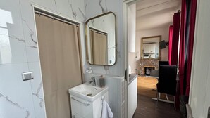 A bathroom with a white sink, mirror, and beige shower curtain.