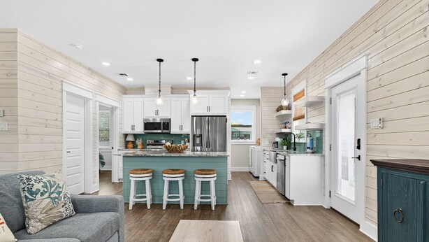 A modern kitchen with white cabinets, a teal island, and bar stools. - Coastal Retreat 3 Bedroom Home (Rockport)
