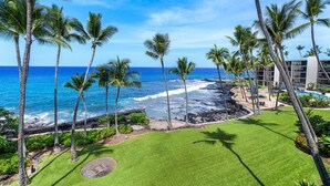 Un resort con piscina, palmeras y vista al océano.
