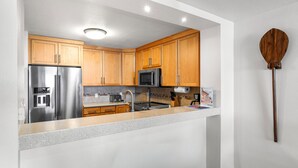 Una cocina compacta con armarios de madera, electrodomésticos de acero inoxidable y decoración de pared con un remo de madera.