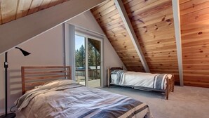 A bedroom with two beds, a sloped ceiling, and a large window. - Sagebrush Cottage 3 Bedroom Chalet (South Lake Tahoe)