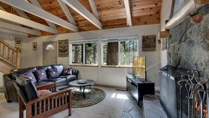 A cozy living room with a fireplace, a leather sofa, a coffee table, and a stone fireplace surround. - Sagebrush Cottage 3 Bedroom Chalet (South Lake Tahoe)