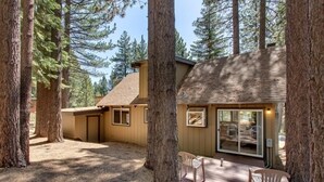 A cabin with a deck, surrounded by tall trees. - Sagebrush Cottage 3 Bedroom Chalet (South Lake Tahoe)