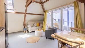A spacious living area with a high ceiling, a sofa, a dining table, and a view of the outside balcony. - Bright Historic Loft in the Heart of Willemstad (Willemstad)
