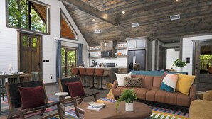 A spacious living area with a high ceiling, wooden beams, a large sofa, a coffee table, and a kitchen area with modern appliances. - Oakhaven Fell - Couples Retreat - Sauna - Cold Plunge - Hot Tub (Broken Bow)