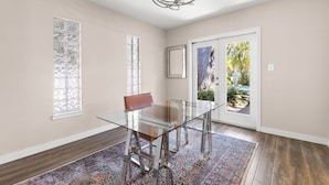 Une salle à manger avec une table en verre, des chaises et un tapis à motifs.