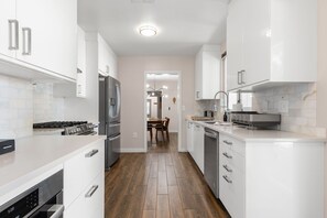 Una cocina moderna con armarios blancos, electrodomésticos de acero inoxidable y suelo de madera.