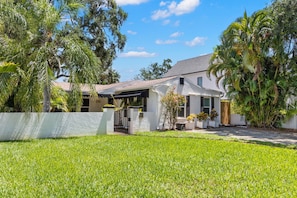 A modern house with a white exterior, a covered patio, and a well-maintained lawn.