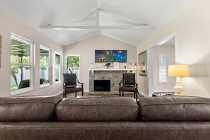 A living room with a fireplace, two armchairs, a sofa, and a lamp.