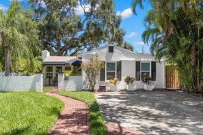 A single-story house with a white exterior, a brick pathway leading to the front door, and a well-maintained lawn.