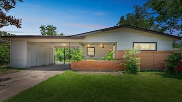 Einbungalow mit einer überdachten Garage, einer Ziegelmauer und einem gepflegten Rasen.