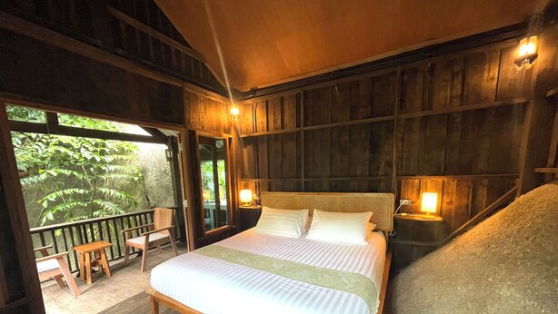 A wooden-framed bedroom with a bed, bedside lamps, and a view of greenery outside. - Peaceful, air-conditioned jungle bungalow - less than 5mins from Lamai beach (Chang Wat Surat Thani)