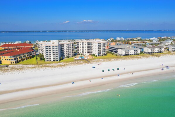 A coastal hotel with multiple buildings, a beach, and clear blue water.