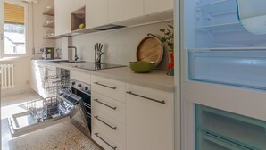A modern kitchen with white cabinets, a dishwasher, an oven, and a refrigerator. - Green Paradise by Varenna Holidays (Lierna)