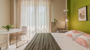 A hotel room with a bed, a desk, a chair, a lamp, and a window with curtains. - Green Paradise by Varenna Holidays (Lierna)