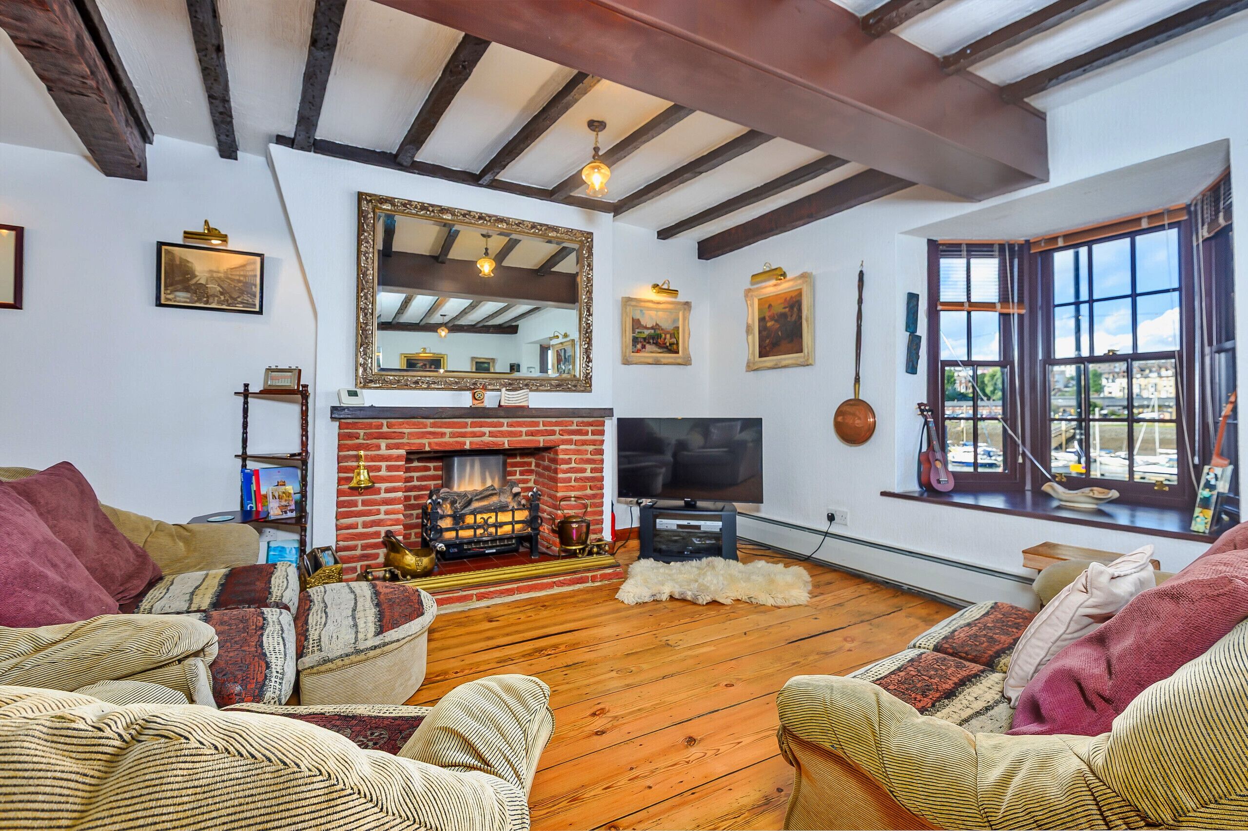 A cozy living room with a fireplace, wooden floors, and comfortable seating.