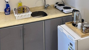 A compact kitchen with grey cabinets, a sink, a kettle, and a small stove. -  Nozzle Al Matal Serviced apartments  (Abha)