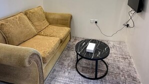 A living room with a sofa, a coffee table, and a TV mounted on the wall. -  Nozzle Al Matal Serviced apartments  (Abha)