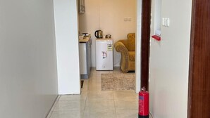 A hallway with a tiled floor leading to a kitchen area with a refrigerator and a coffee maker. -  Nozzle Al Matal Serviced apartments  (Abha)