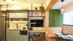 A modern kitchen with a built-in stove, a dining area with a table and chairs, and a green wall. - Setin Pamplona R (Sao Paulo)