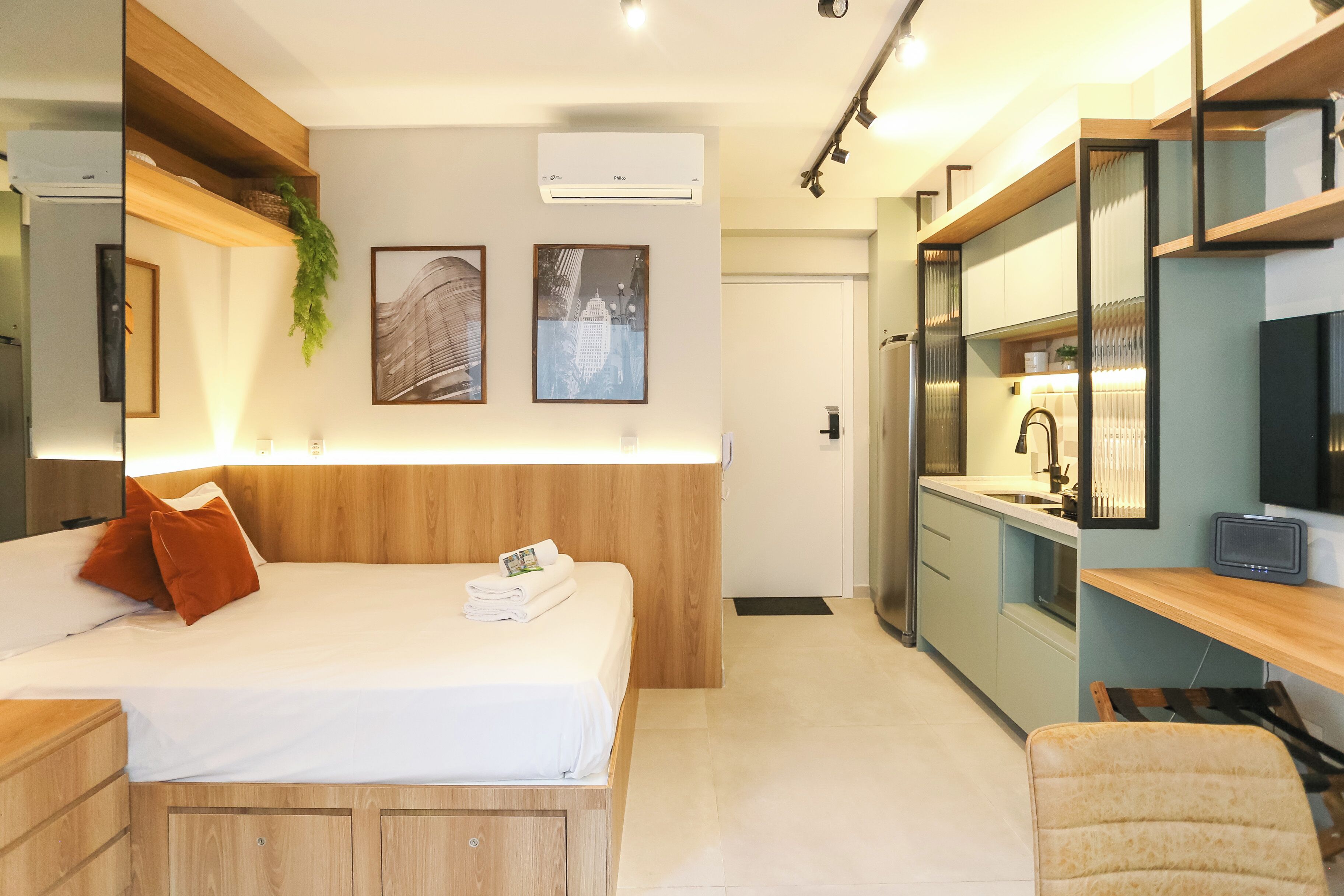 Een moderne hotelkamer met een houten bed, een bureau en een kitchenette.