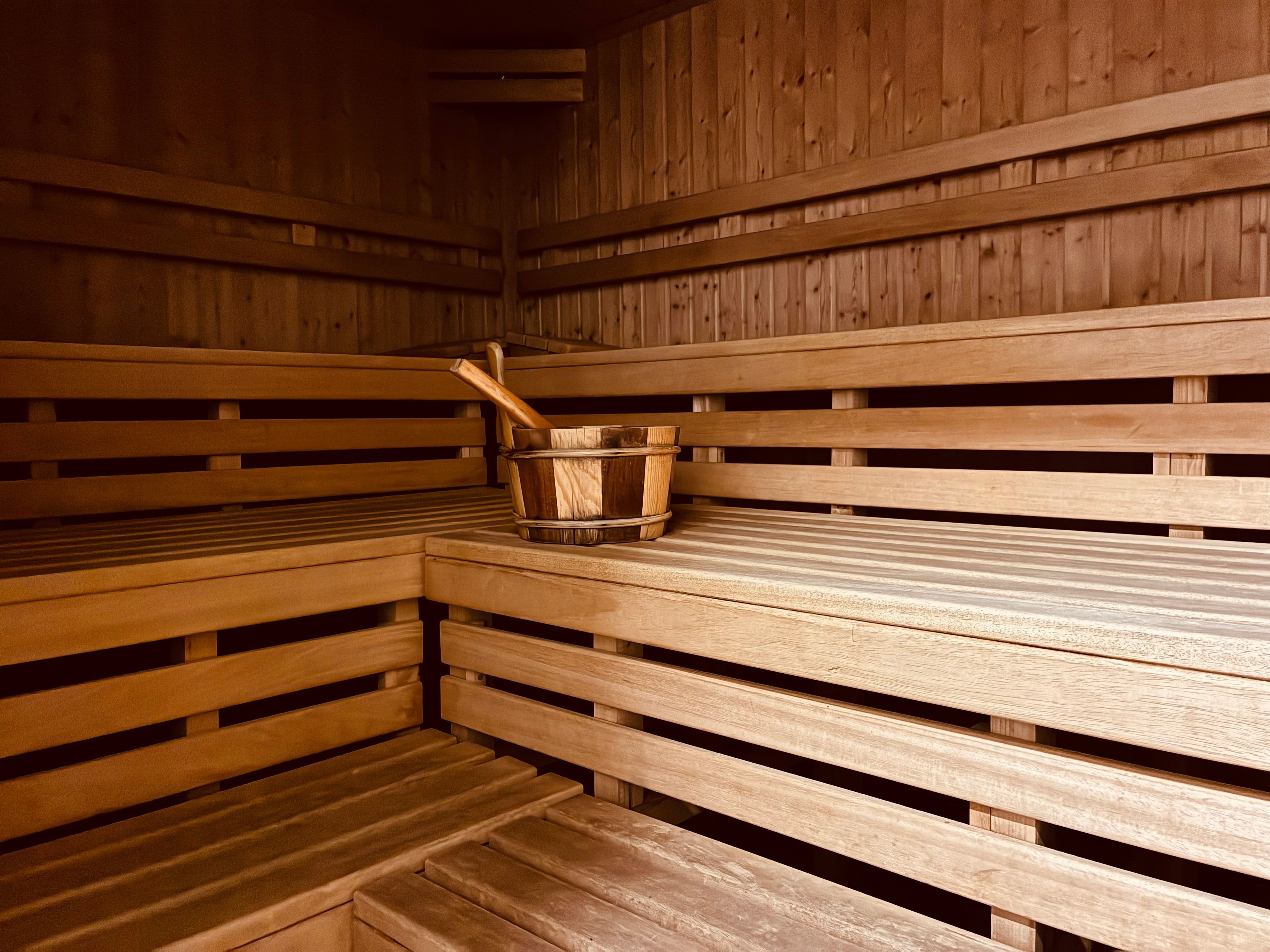 Eine Sauna mit Holzbänken und einem Metalleimer mit einem Holzgriff.