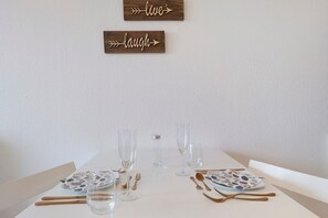 A dining table set with clear glassware, plates, and cutlery, with two wooden signs above reading 'live' and 'laugh.'