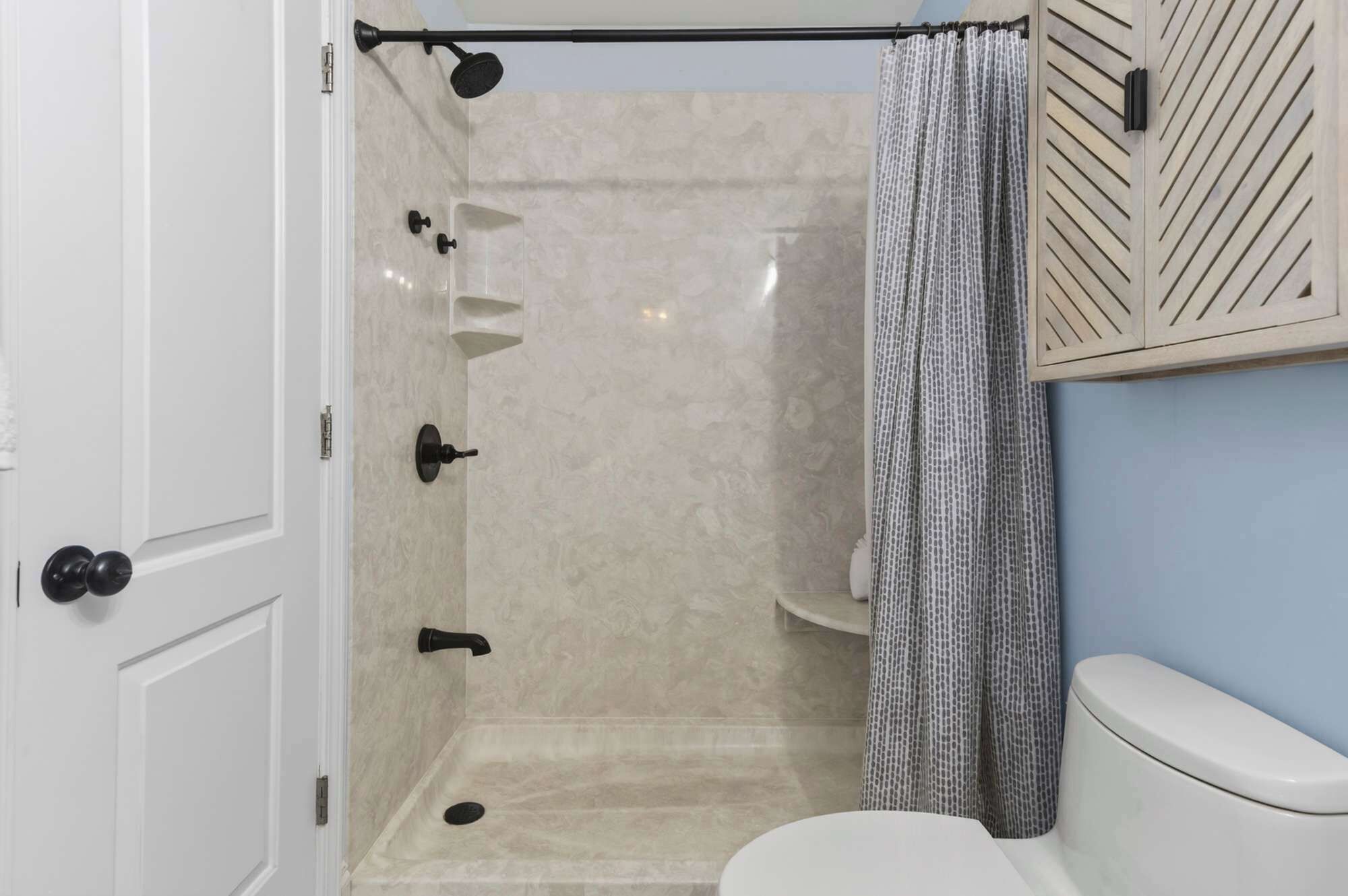 A bathroom with a shower, toilet, and a towel rack.