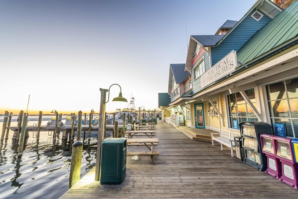 A wooden pier with benches and picnic tables, a sign for 'Nautical Delights', and a view of the water. - Holiday Isle - Private Beach - Special Offer! (Destin)
