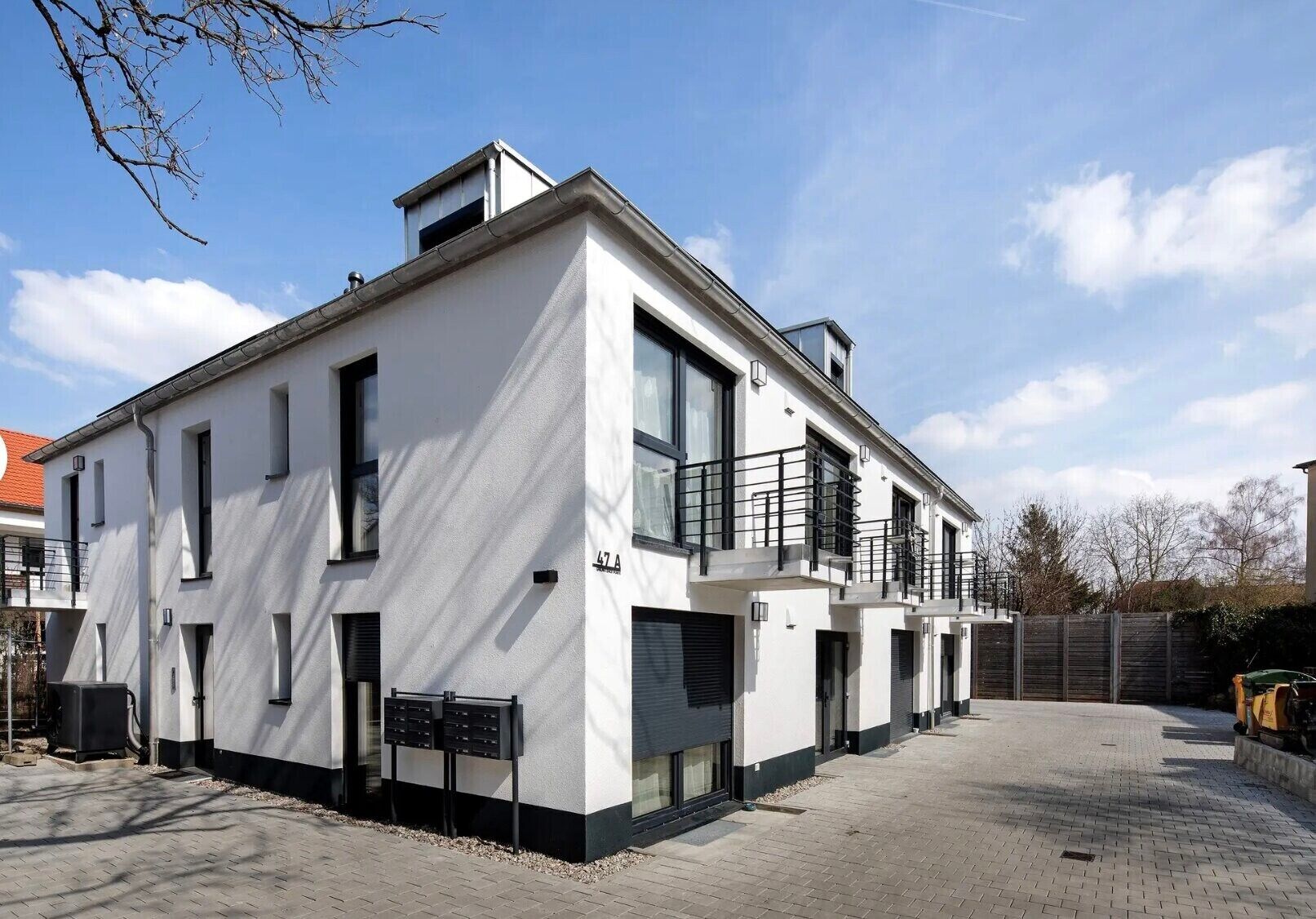 A modern two-story building with a flat roof, large windows, and a balcony.