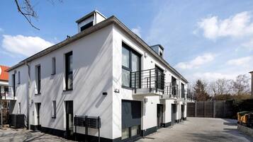 A modern two-story building with a flat roof, large windows, and a balcony.
