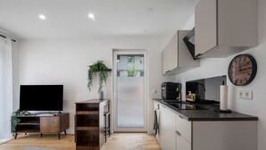Una cocina moderna con una televisión de pantalla plana, armarios de madera y un reloj en la pared.