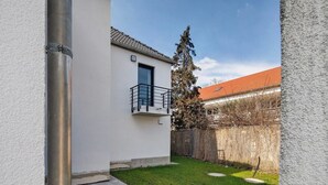 Un edificio residencial con balcón, patio cercado y un árbol.
