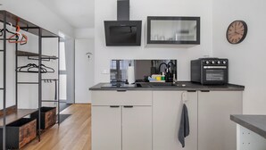 Una cocina moderna con armarios blancos, una campana extractora negra, un horno integrado y un reloj montado en la pared.