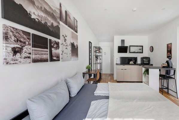 A modern room with a bed, a desk, and a kitchenette.