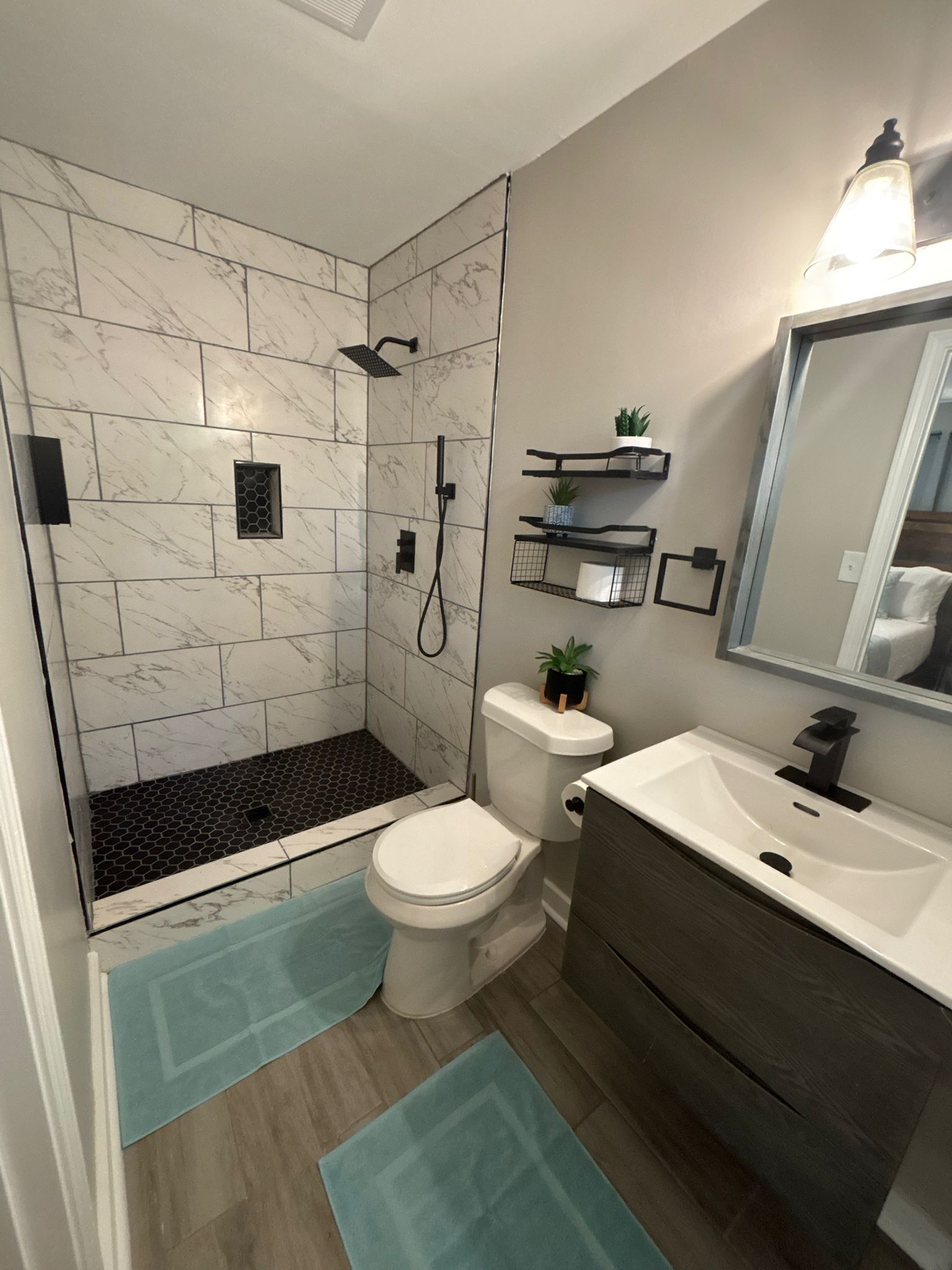 Een badkamer met douche, toilet, wastafel en spiegel.