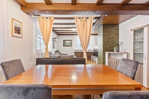 A dining area with a wooden table and chairs, a sofa, and a kitchen area in the background. - Haus Tannenberg Holiday Apartment Elias' Nestli (Todtnau)