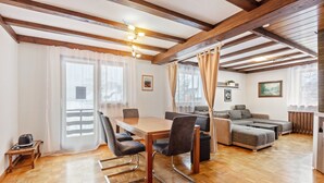 Una habitación con suelo de madera, una mesa de comedor con sillas, un sofá y una cama.