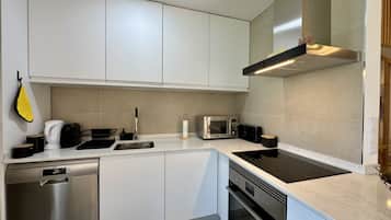 Una cocina moderna con electrodomésticos de acero inoxidable, lavavajillas y horno empotrado.