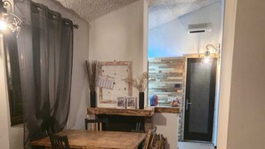 A dining area with a wooden table and chairs, a red sofa, and a wall-mounted clock. - Cozy apartment in the Umbrian countryside, small animals welcome! (I Prati)