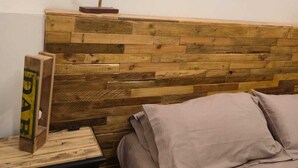 A bedroom with a wooden headboard, a nightstand with a lamp, and a painting on the wall. - Cozy apartment in the Umbrian countryside, small animals welcome! (I Prati)