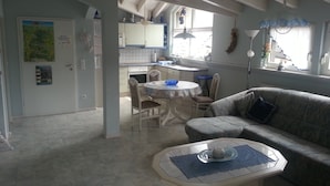 Amplia sala de estar con un sofá, una mesa de comedor y una cocina al fondo.