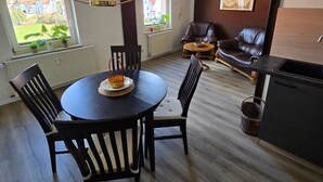 Un coin repas avec une table ronde, des chaises, un luminaire suspendu et une vue par la fenêtre.