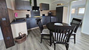 Une cuisine moderne avec des meubles de couleur sombre, un îlot central et un coin repas comprenant une table ronde et quatre chaises.