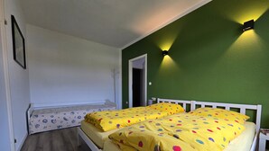 Une pièce avec un lit, une porte et un luminaire fixé au mur.