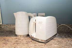 A kitchen counter with a white electric kettle and toaster.