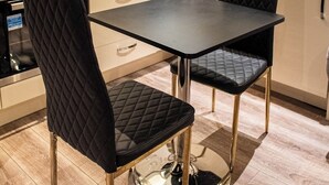 Une cuisine moderne avec une table et des chaises noires, des appareils en acier inoxydable et des meubles de couleur claire.