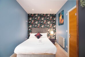 A bedroom with a bed, a nightstand, a lamp, and a door. - Contemporary Kelham 1-Bed Pet-Friendly Apartment (Sheffield)