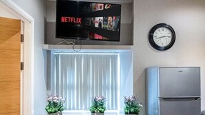 Une cuisine moderne équipée d’un téléviseur intégré qui diffuse Netflix, d’une horloge et d’un réfrigérateur.
