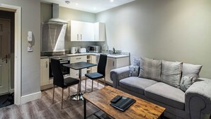 Un espace de vie compact comprenant un coin cuisine, un coin repas avec deux chaises, un canapé et une table basse.